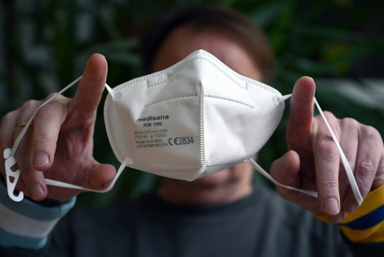 An illustration shows a man showing a FFP2 face mask in Dortmund, western Germany, on January 19, 2021. - German Chancellor Angela Merkel and leaders of Germany's 16 states are expected on january 19 to extend and tighten a partial lockdown beyond January, as fears grow over virus variant strains believed to be more contagious. Draft measures seen ahead of the emergency talks include prolonging current restrictions until at least mid-February, requiring medical masks on public transport and in shops, and increasing pressure on employers to allow staff to work from home where possible. (Photo by Ina FASSBENDER / AFP)