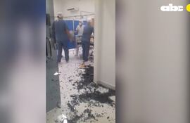 Personal de blanco del Hospital de Villa Elisa recogen los restos de cristal luego de un incidente violento con un familiar de un paciente fallecido.