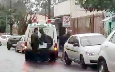 El chofer y el administrador  alzan  unas cajas a la parte posterior del móvil de emergencia.