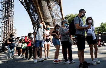 Visitantes que llevan máscaras protectoras hacen cola mientras esperan la reapertura parcial de la Torre Eiffel el 25 de junio de 2020 en París, mientras Francia alivia las medidas de bloqueo tomadas para frenar la propagación del COVID-19.