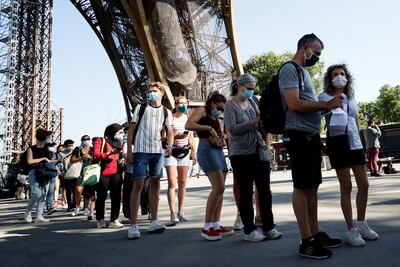Visitantes que llevan máscaras protectoras hacen cola mientras esperan la reapertura parcial de la Torre Eiffel el 25 de junio de 2020 en París, mientras Francia alivia las medidas de bloqueo tomadas para frenar la propagación del COVID-19.