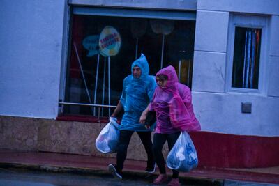 Personas cruzan una calle durante las fuertes lluvias causadas por Eta en Florida.