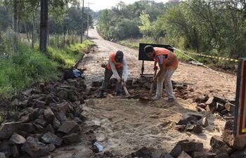 Obreros remueven y reparan parte del empedrado preexistente para el vertido de la capa final de asfalto, en el camino de acceso al barrio Chaipé de Encarnación.