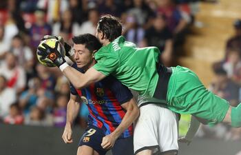 El guardameta macedonio del Rayo Vallecano, Stole Dimitrievski (d) atrapa el balón junto al delantero del Barcelona Robert Lewandowski durante el partido correspondiente la Jornada 31 de LaLiga que disputaron Rayo Vallecano y FC Barcelona el miércoles en el Estadio de Vallecas, en Madrid. EFE/Kiko Huesca