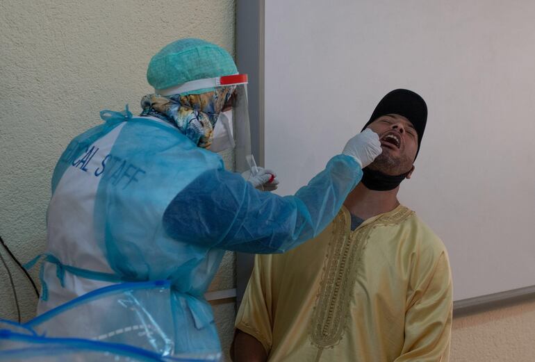 Un trabajador sanitario toma una muestra de saliva de un conductor de taxis para saber si tiene coronavirus, en Rabat, Marruecos.