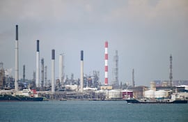 Un petrolero (derecha) navega frente a las refinerías de petróleo de Shell en la isla de Bukom, frente a Singapur.