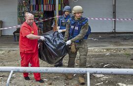 Médicos retiran el cuerpo de una víctima tras el ataque de un misil en una parada de buses cercana a un mercado de Kharkiv, Ucrania.