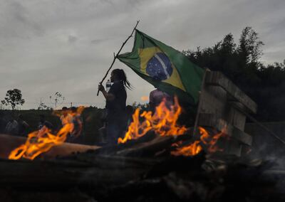 Una mujer sostiene una bandera de Brasil durante bloqueo de camioneros hoy, en la carretera Presidente Dutra, cerca a Volta Redonda (Brasil). Los camioneros de Brasil bloquearon al menos 200 puntos en carreteras de todo el país entre la noche del domingo y este lunes, en protesta por la derrota en las elecciones del presidente Jair Bolsonaro, según informaron las autoridades. (EFE)