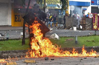 Un policia es alcanzado por una bomba incendiaria durante un enfrentamiento con manifestantes en Cali, el lunes.