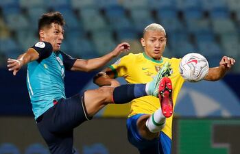 El ecuatoriano Alan Franco (i) logra puntear el balón anticipándose al brasileño Richarlison, durante el partido de ayer disputado en Goiania.