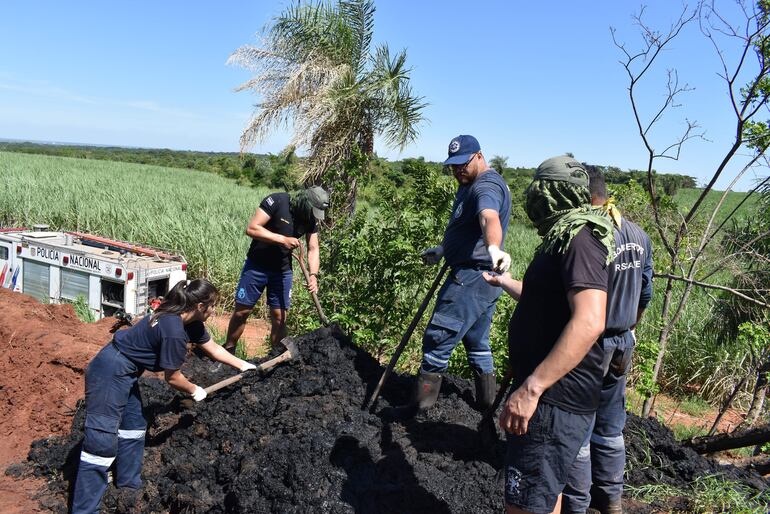 Momentos en que uno de los bomberos pasa uno de los restos óseos encontrados hoy en medio del lodo sacado del tajamar