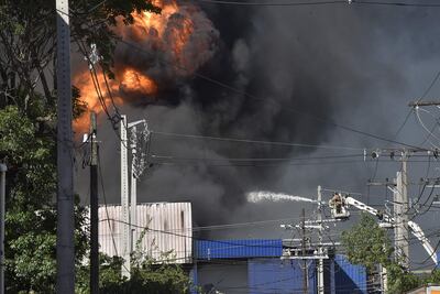 Un bombero montado en un brazo hidráulico tira chorros de agua hacia el foco del siniestro.