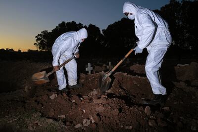 Trabajadores del cementerio Sao Franciso Xavier en Río de Janeiro, Brasil, cavan una fosa vistiendo trajes de protección contra el coronavirus.