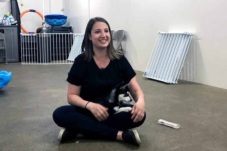 La entrenadora de perros Hannah Richter se sienta con Lucy en el piso de la tienda Beasty Feasty en Nueva York.