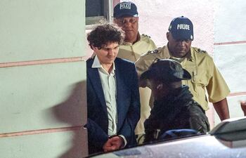 El fundador de FTX, Sam Bankman-Fried (izquierda), es llevado esposado por agentes de la Policía Real de Bahamas en Nassau, Bahamas.