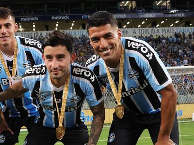 El delantero uruguayo de Gremio, Luis Suárez (D), posa para una foto con sus compañeros de equipo, entre ellos Mathías Villsanti, después de derrotar a Sao Luiz durante el último partido de fútbol de la Recopa Gaucha.