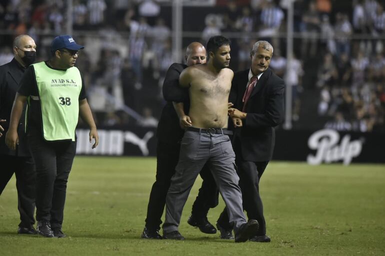 El hincha de Guaraní que ingresó al campo es sujetado y retirado por la seguridad privada de La Huerta.