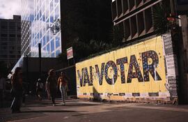 Varias personas caminan frente a un mural sobre las elecciones, en Sao Paulo (Brasil). Los comicios presidenciales, legislativos y regionales en Brasil transcurren este domingo con normalidad en sus primeras horas, con pocos casos registrados de problemas en las urnas electrónicas y de delitos electorales, comunicaron las autoridades. Las elecciones de 2022, las más polarizadas desde que Brasil recuperó la democracia en 1985, se han caracterizado por un clima de crispación entre el exmandatario Luiz Inácio Lula da Silva, el gran favorito en las encuestas de intención de voto, y el actual presidente, Jair Bolsonaro, quien busca la reelección. EFE/ Ettore Chiereguini