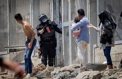 Policías españoles intentan dispersar a migrantes en la localidad de Ceuta, en la frontera entre España y Marruecos, este martes.