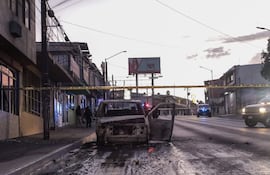 Policías acordonan la zona en donde se halló un vehículo incinerado en Tijuana, Baja California (México). Al menos 19 vehículos, entre autos particulares, unidades de transporte público y de carga, fueron incendiados este viernes presuntamente por grupos de la delincuencia organizada, en el estado mexicano de Baja California.