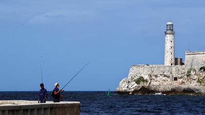 Dos jóvenes pescan frente al faro del castillo del Morro, en La Habana (Cuba).