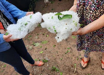 Dos pobladoras de la compañía Naranjaty de Horqueta muestran granizos acumulados que cayeron en la zona.
