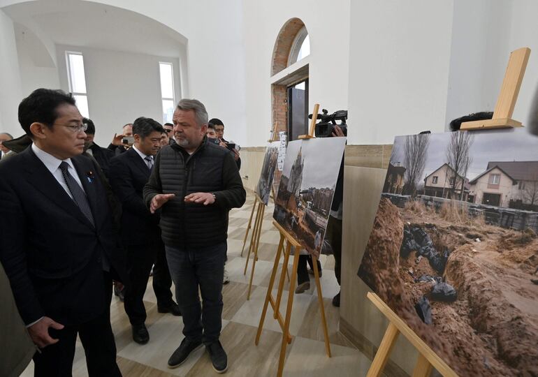 El premier japonés Fumio Kishida (i) observa una fotografía en la que se muestra la fosa común donde fueron hallados cadáveres de decenas de personas víctimas de una masacre en la localidad ucraniana de Bucha. (AFP)