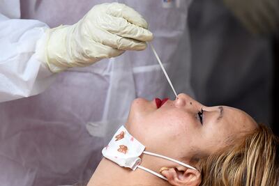 Un trabajador médico toma una muestra de una mujer para un test de COVID-19 en Katmandú, Nepal.