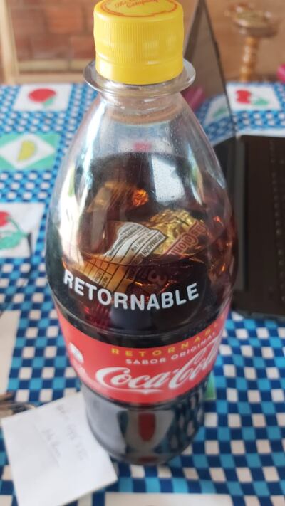 En el interior de la botella se observan envoltorios de alimentos.
