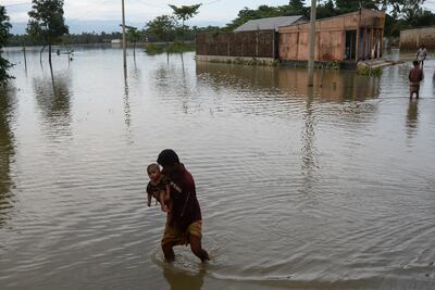 Un hombre con un niño en brazos cruza un área inundad en Sunamgong, Bangladés.