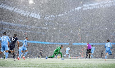 El arquero Ederson, del Manchester City, sale jugando con un compañero en el campo del estadio Etihad, que estaba cubierto por nieve.