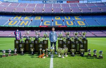 El futbolista Gerard Piqué con los 30 títulos que ganó con el FC Barcelona, en el césped del Camp Nou - FCB