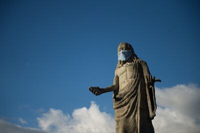 Vista de una estatua que representa al Santo Cristo de la Salud de Petare, con una mascarilla, en el barrio Petare en Caracas.