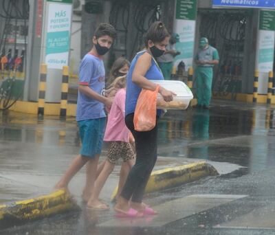 Integrantes de una familia cruzan una avenida de la ciudad de Asunción en medio del  chaparrón, que trajo alivio a la ciudadanía que ansiaba ya que haya lluvia.