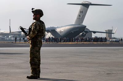 Un soldado estadounidense en guardia en el aeropuerto internacional de Kabul, mientras una aeronave de la Fuerza Aérea estadounidense se prepara para evacuar a más personas.
