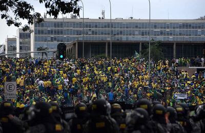 Los partidarios del expresidente brasileño Jair Bolsonaro que invaden varios edificios gubernamentales se enfrentan a las fuerzas de seguridad (en primer plano) en Brasilia el 8 de enero de 2023.