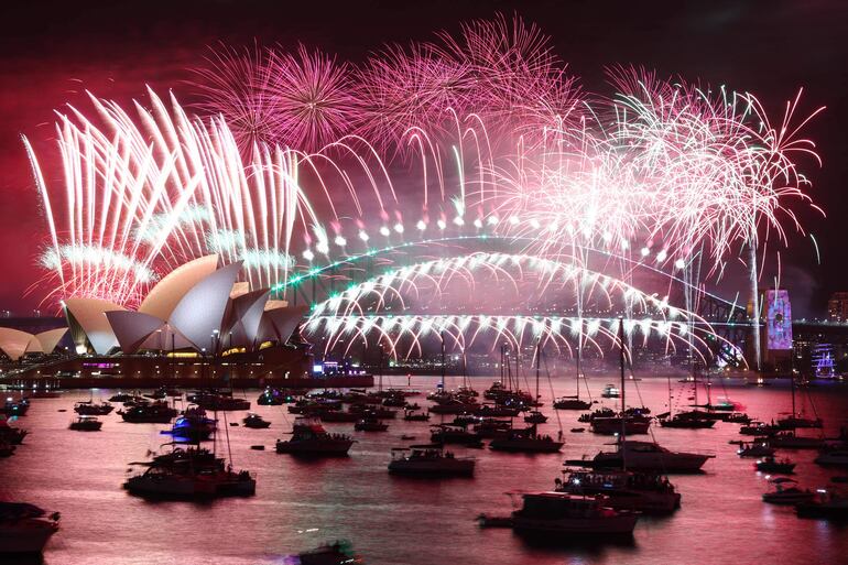 Los fuegos artificiales de Nochevieja iluminan el cielo sobre la Ópera de Sídney (izquierda) y el puente Harbour Bridge durante la exhibición de fuegos artificiales en Sídney el 1 de enero de 2023. Foto: AFP