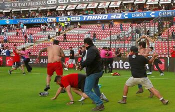 Un aficionado del Querétaro se dispone a agredir con una barra a un simpatizante del Atlas, que intenta levantarse del suelo tras ser golpeado por otro hincha. Fue en el fútbol mexicano.