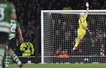 El arquero del Arsenal Aaron Ramsdale vuela pero no llega a alcanzar el balón rematado por Pedro Goncalves, quien marcó un golazo desde la media cancha para el empate 1-1 del Sporting de Portugal.