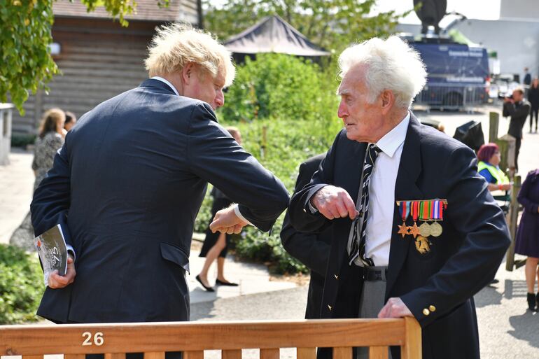El primer ministro británico Boris Johnson saluda con un golpe de codo a un veterano luego de una recordación en el memorial de Alrewas, en el 75 aniversario de la Victoria sobre Japón.