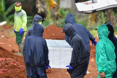 Esta fotografía tomada el 6 de mayo de 2020 muestra sepultureros llevando el ataúd de una víctima del coronavirus COVID-19 en el cementerio Pondok Ranggon, Indonesia.