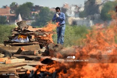 A family member offers prayers during cremation of his loved one who died due to the Covid-19 coronavirus at a cremation ground in Allahabad on May 8, 2021, as India recorded more than 4,000 coronavirus deaths in a day for the first time. (Photo by Sanjay KANOJIA / AFP)