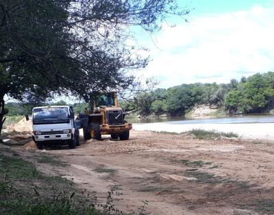 Un tractor carga la arena a una camión tipo tumba en el sector de la playa municipal ubicada sobre el río Tebicuary.
