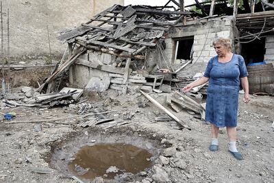 Una mujer muestra el impacto de un proyectil de artillería en su casa, en la región de Tavush, escenario estos días de enfrentamientos entre Azerbaiyán y Armenia.