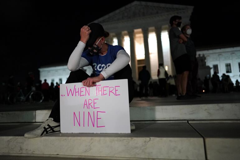 Una mujer sostiene un cartel con la frase "...cuando haya nueve", en alusión a la respuesta que dio Ruth Bader Ginsburg a la pregunta de ¿cuándo habrá suficientes mujeres en la Corte Suprema de Estados Unidos.