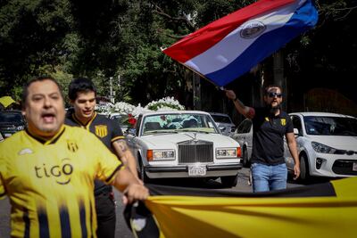 Aficionados del Guaraní acompañan hoy, domingo, el carro fúnebre que transporta los restos del asesinado fiscal Marcelo Pecci, frente a la sede del club en Asunción.
