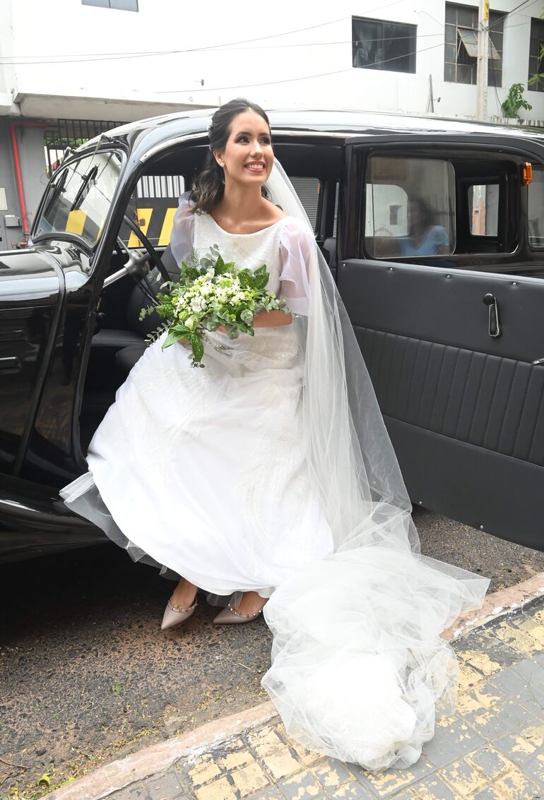 La novia lució un vestido de líneas románticas creación de Karina Pecci, complementando con un exclusivo tocado realizado por Sady Báez de Villalonga, tía del novio. 