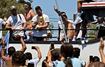Lionel Messi de Argentina saluda a los fanáticos que sostienen el Trofeo de la Copa Mundial de la FIFA mientras el equipo desfila a bordo de un autobús después de ganar el torneo de la Copa Mundial de Qatar 2022 en Buenos Aires, Argentina el 20 de diciembre de 2022.