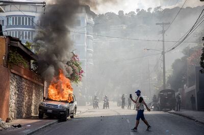 A car burns as demonstrators march in Port-au-Prince on February 14, 2021, to protest against the government of President Jovenel Moise. - Several thousand people demonstrated Sunday in the Haitian capital Port-au-Prince, saying the government was trying to establish a new dictatorship and denouncing international support for President Jovenel Moise. The protests were mostly peaceful, although a few clashes broke out between some demonstrators and police, who fired tear gas and rubber bullets. (Photo by Valerie Baeriswyl / AFP)