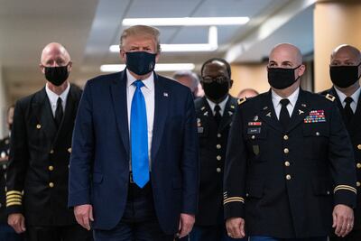 El presidente estadounidense Donald Trump y funcionarios militares, todos con mascarillas, en una visita a un centro médico militar en Bethesda, Maryland.